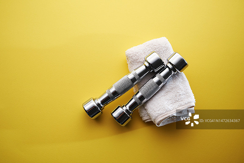 黄色背景上的银色哑铃和毛巾，马来西亚图片素材