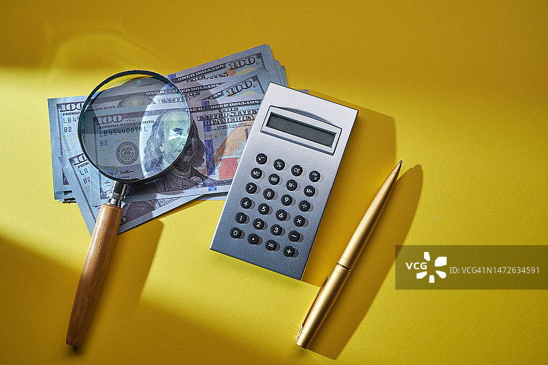 美元纸币上的计算器、笔和放大镜，马来西亚图片素材
