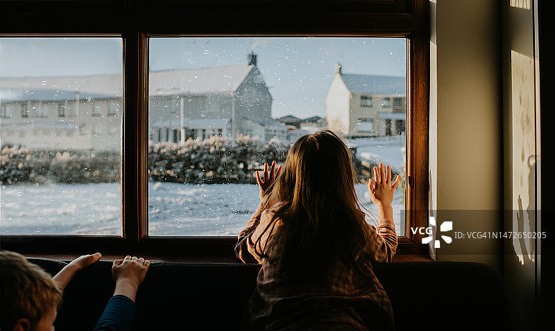 孩子们敬畏地凝视窗外，看着暴风雪图片素材
