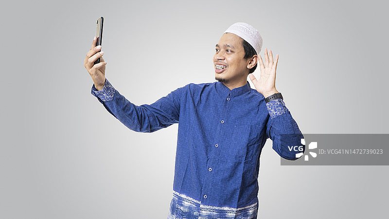 使用智能手机进行视频通话的亚洲穆斯林青年男子图片素材