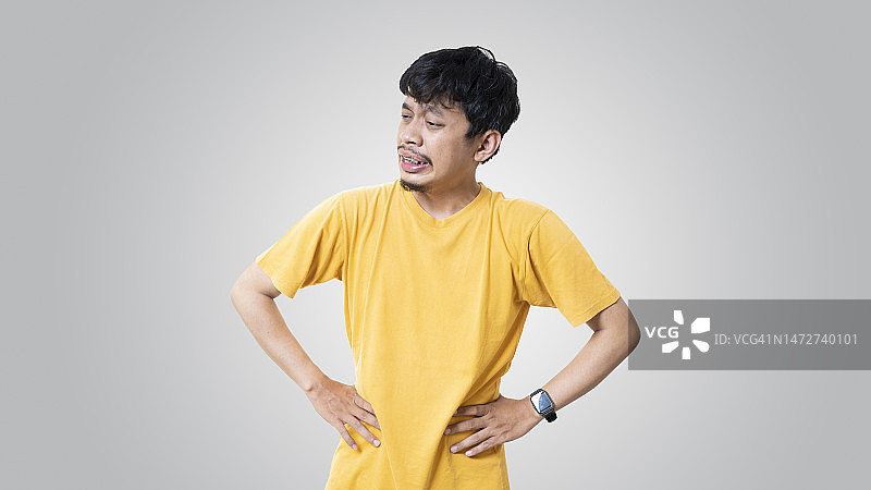 胃痛的男人靠在灰色背景上图片素材