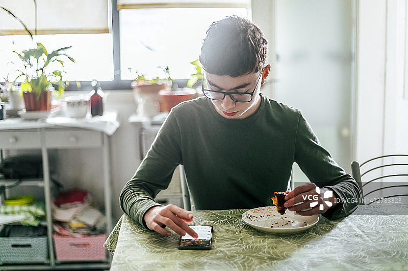 青少年在厨房用手机发短信图片素材
