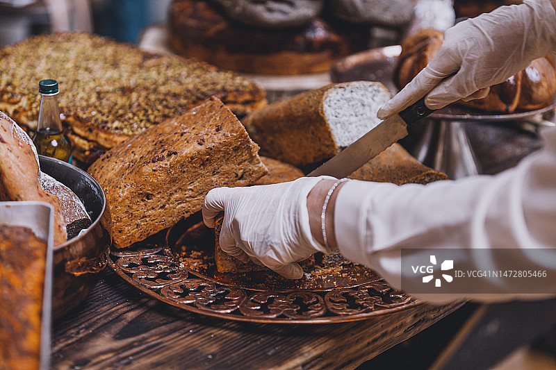 面包师在木桌上手工切割乡村面包图片素材