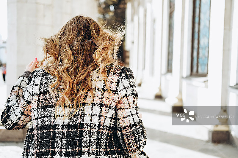 阳光明媚的日子里，在老建筑附近的年轻女子图片素材
