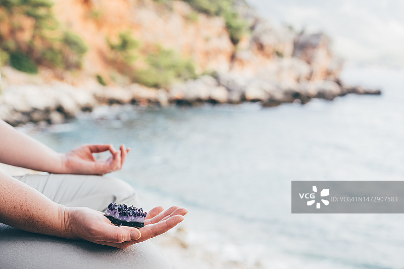女人手握水晶，背景是海图片素材