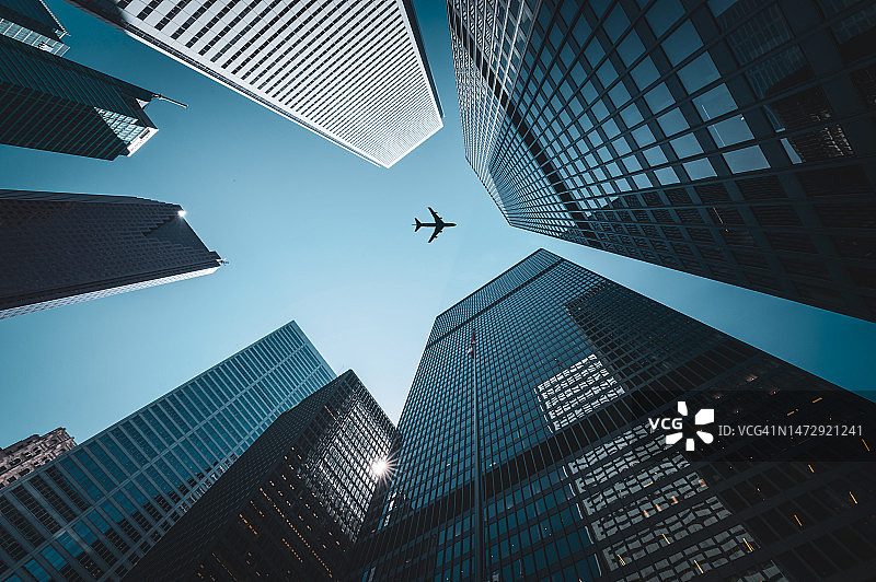 飞机飞过高耸的摩天大楼图片素材