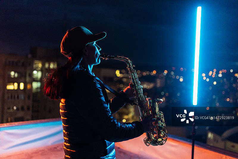 充满激情的女艺术家在屋顶上演奏萨克斯管图片素材