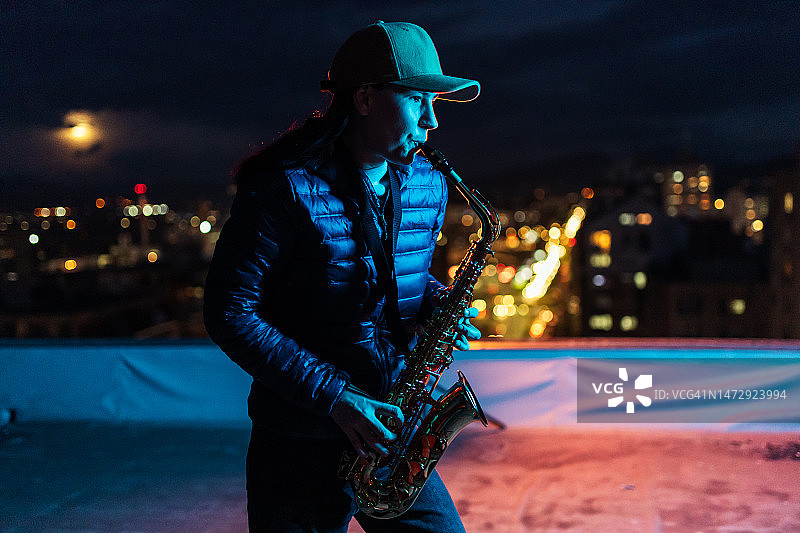 充满激情的女艺术家在屋顶上演奏萨克斯管图片素材
