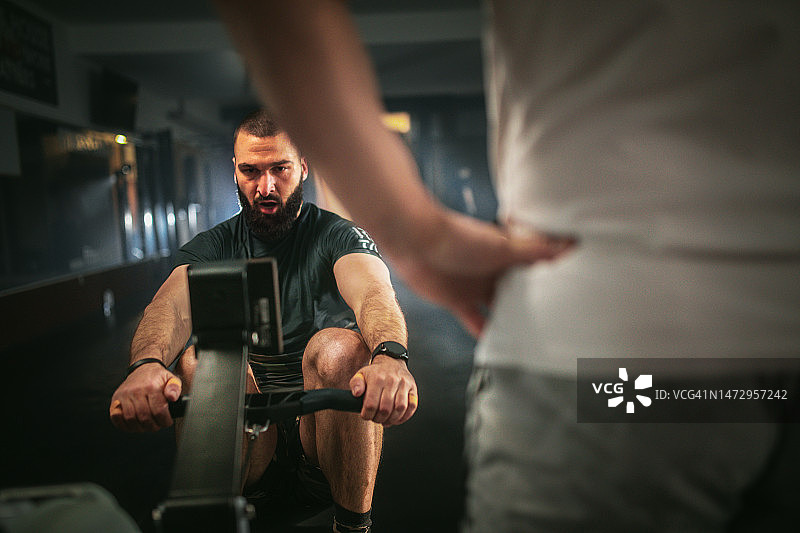 在健身俱乐部使用划船机和自行车的年轻运动员图片素材