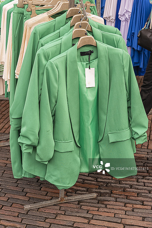 市场上衣架上各种尺寸的绿色女士夹克图片素材