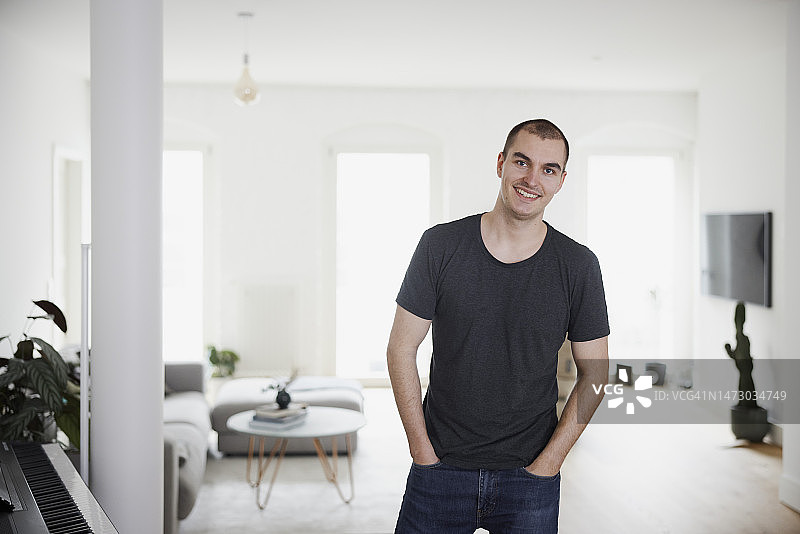 英俊年轻男人在家中双手插兜站立图片素材