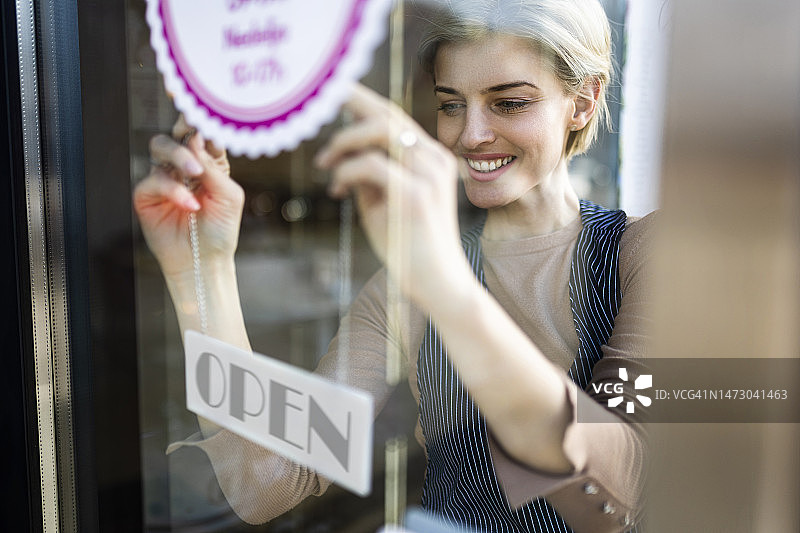 小镇咖啡店的年轻女店主。她正在开店，等待顾客图片素材