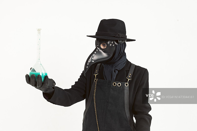 中世纪瘟疫医生手持装有药剂或血清的玻璃容器肖像特写，白色背景隔离，流行病和大流行概念图片素材