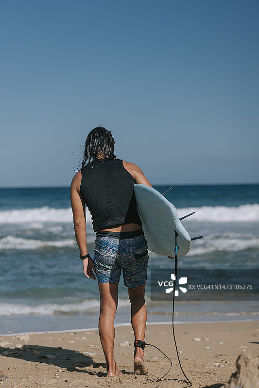 携带冲浪板的中国男冲浪者背面图片素材
