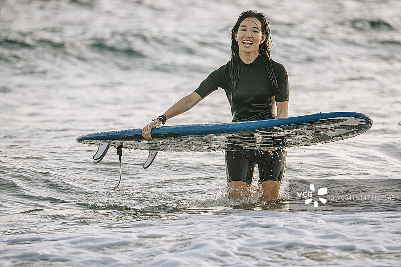满意的中国台湾女性冲浪者在台湾垦丁海滩傍晚冲浪后返回图片素材