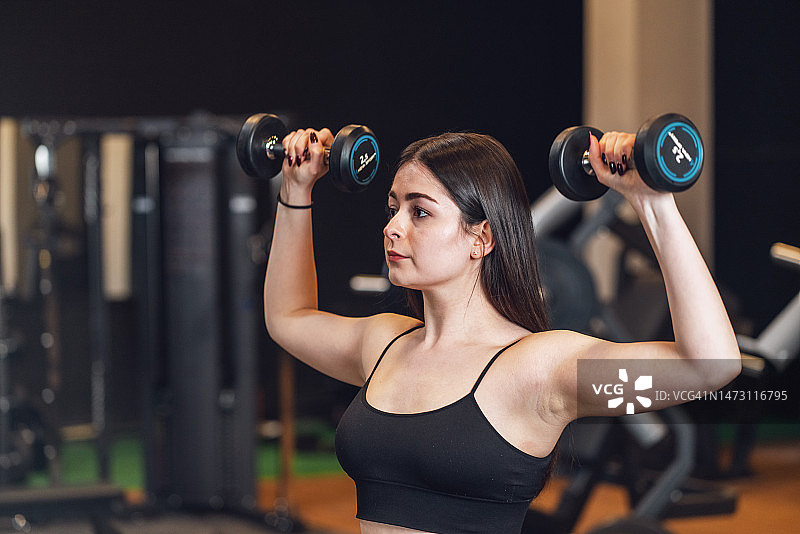 年轻女人在健身房举重图片素材