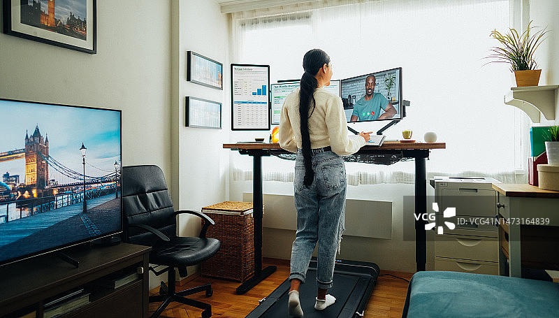 在站立式办公桌家庭办公室进行商务视频通话的女人图片素材