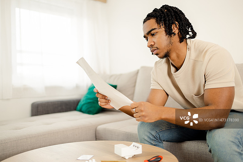 年轻非裔美国男子阅读DIY说明书图片素材