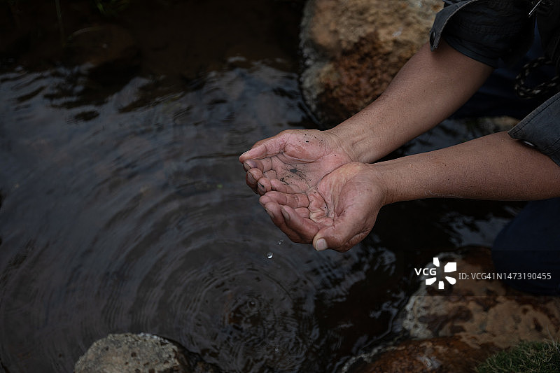 手从河里舀起清水图片素材