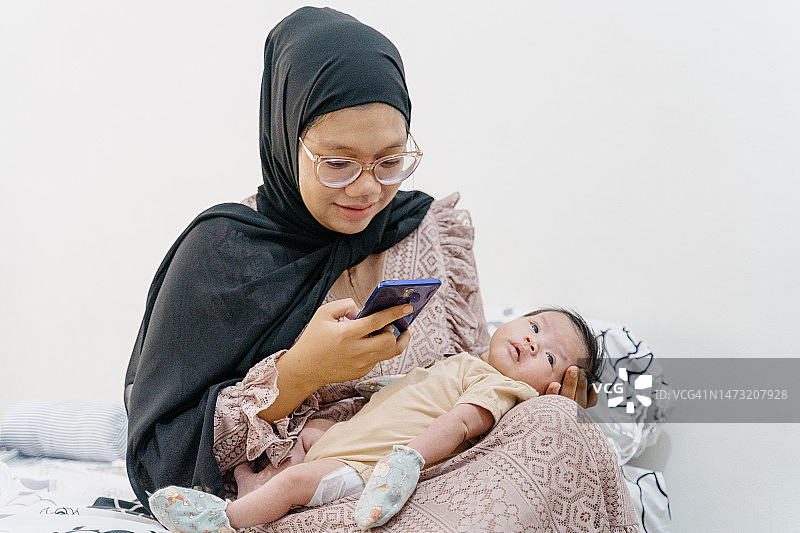 妈妈和新生儿使用智能手机图片素材