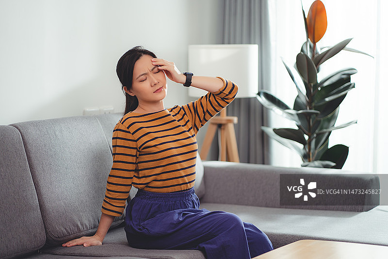 在家中客厅沙发上头痛的亚洲女性图片素材