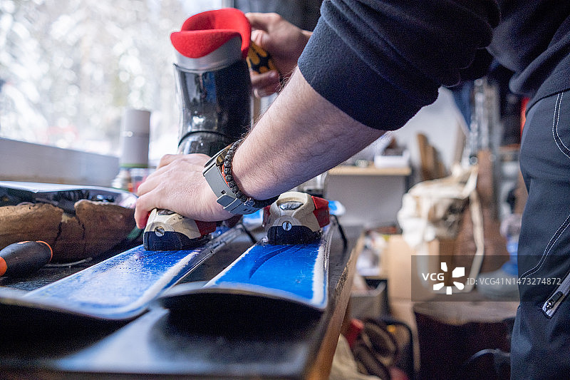 滑雪租赁助理调整滑雪靴上的滑雪板图片素材