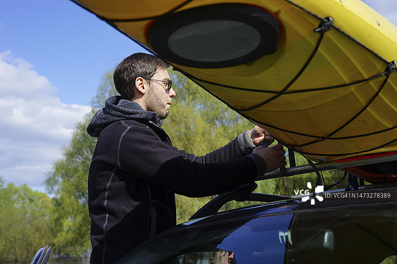 男人修理车顶上的皮划艇图片素材