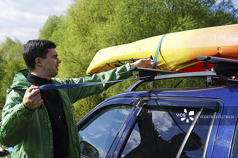 男人修理车顶上的皮划艇图片素材