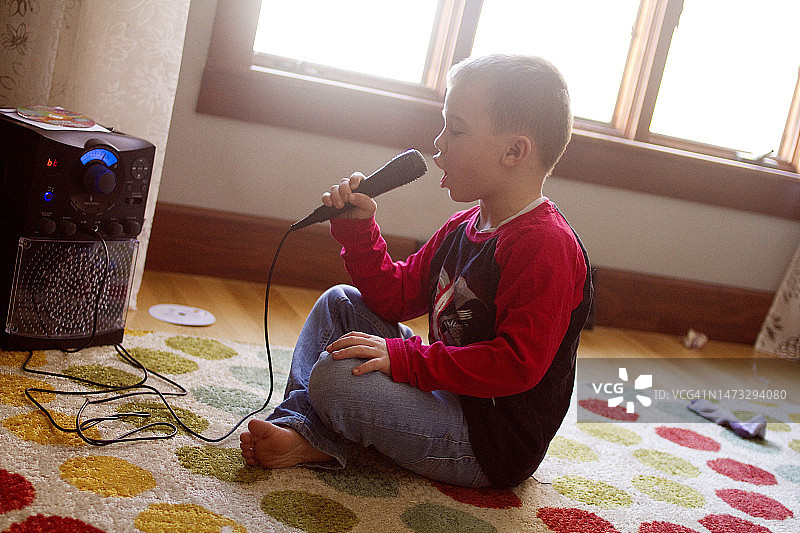 男孩坐在地上用卡拉OK机唱歌图片素材