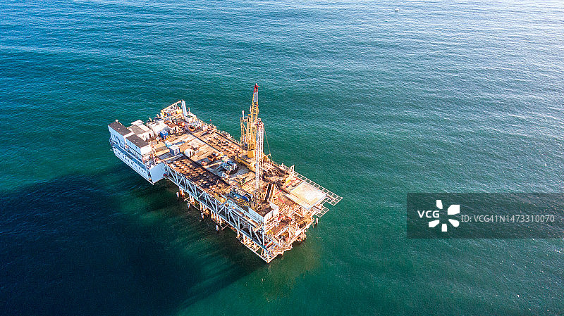 长滩/洛杉矶附近，清晨黄昏时分的近海石油天然气钻井平台与远处货船图片素材