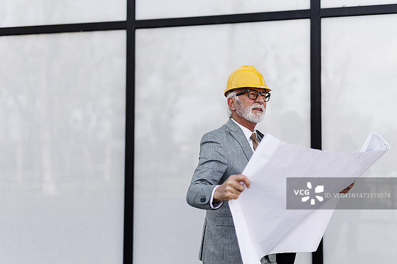 老年建筑师的肖像与户外蓝图图片素材