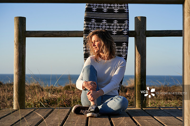 女人坐在冲浪板旁边图片素材