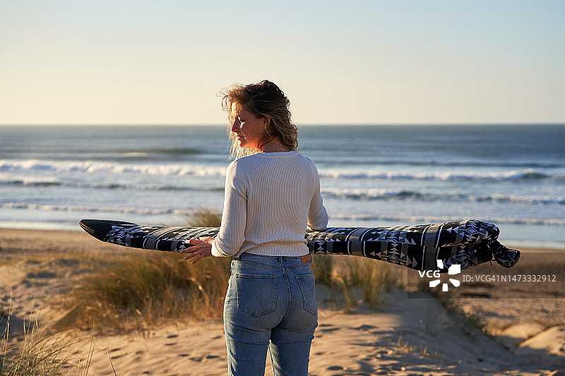 女人在海滩上拿着冲浪板转身图片素材