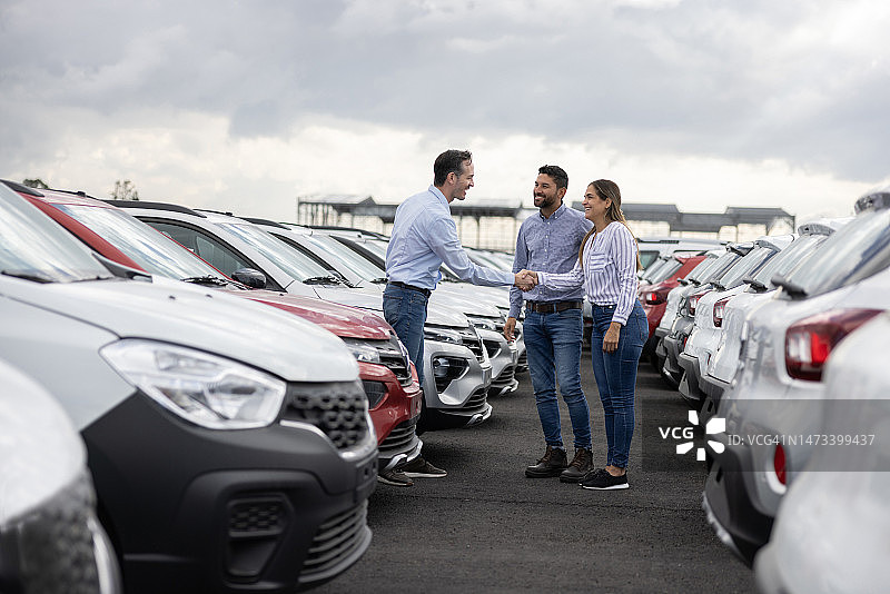 买车后与汽车销售员握手的夫妇图片素材