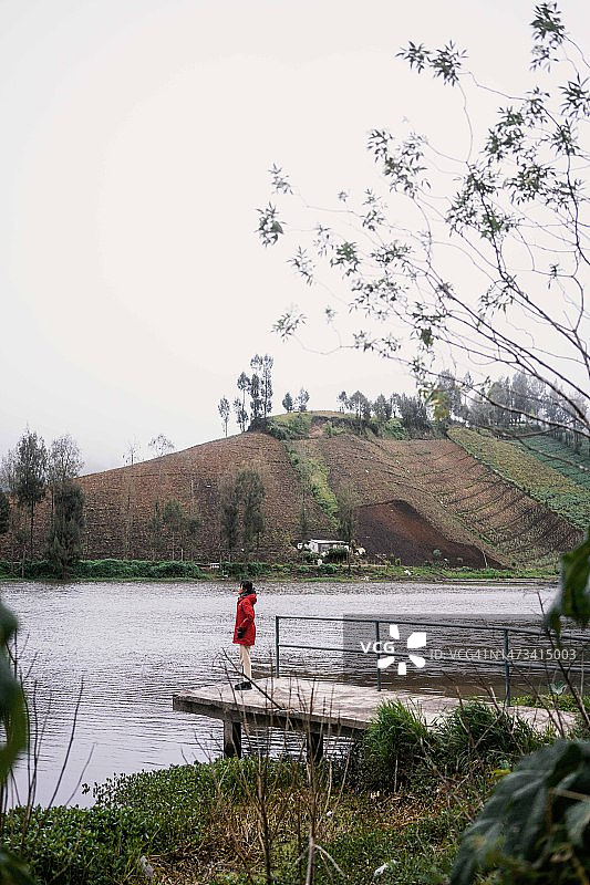 东南亚女孩在拉努帕尼湖的混凝土码头上穿着红色夹克图片素材