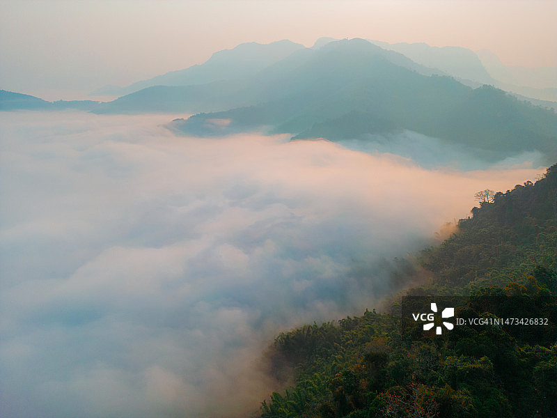 日出时云中喀斯特山脉的鸟瞰图图片素材