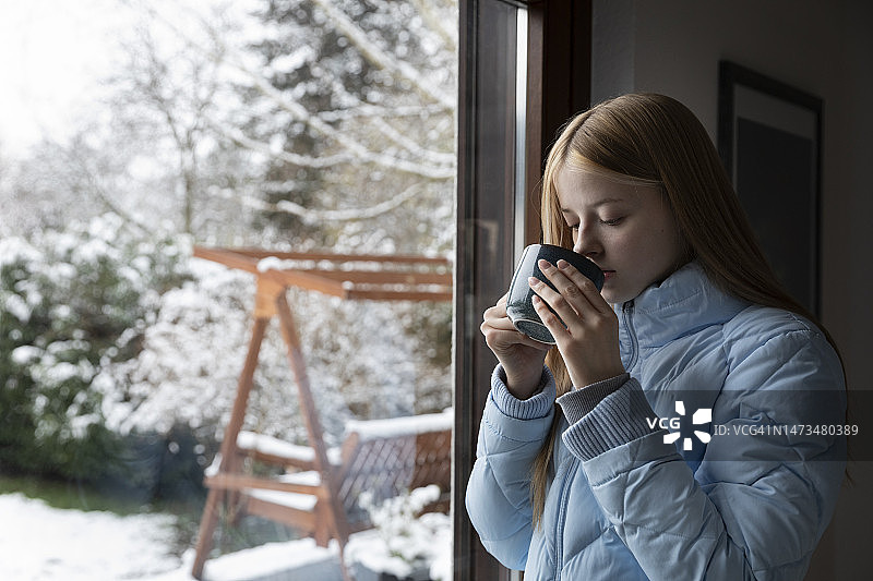 少女在冬日雪景旁喝暖饮图片素材