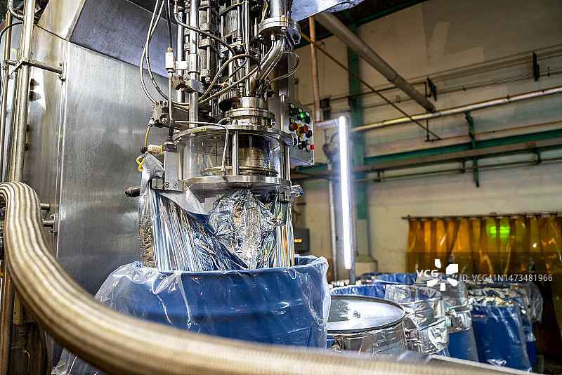 自动无菌灌装机在工业设施中将液体或番茄酱灌装到大型桶中。食品工业。图片素材