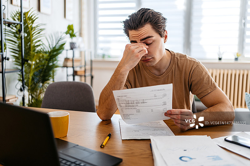 忧心忡忡的年轻人正在家查看财务状况图片素材