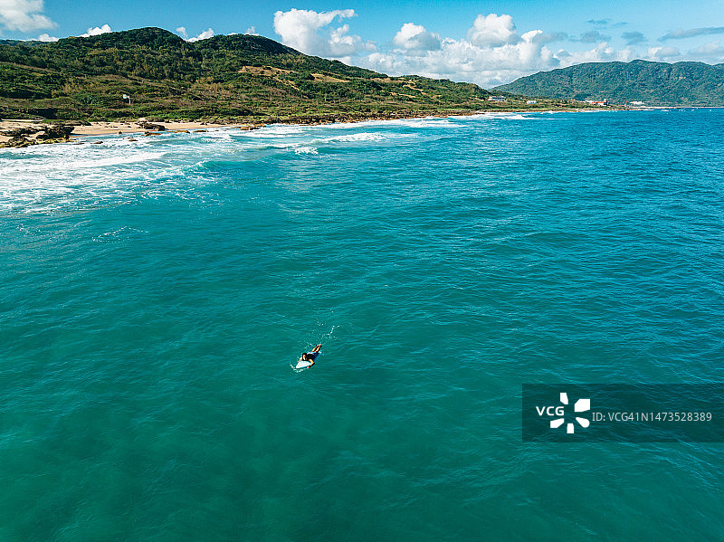 从空中视角看，在蓝色海洋中带着冲浪板的男冲浪者图片素材