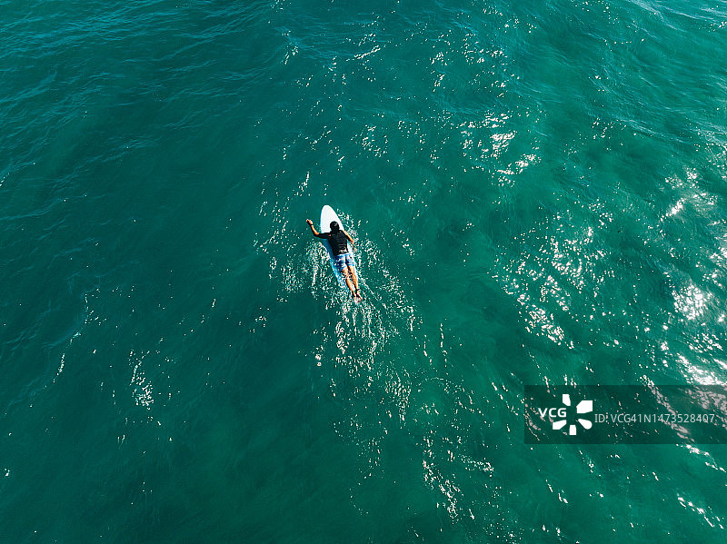 从空中视角看，在蓝色海洋中带着冲浪板的男冲浪者图片素材
