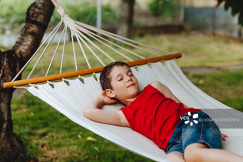 男孩躺在后院的吊床上图片素材