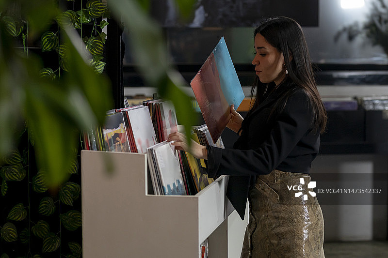 年轻女子在唱片店挑选黑胶唱片图片素材