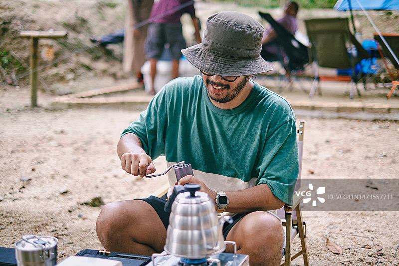 快乐的亚洲男人在露营地研磨咖啡豆图片素材
