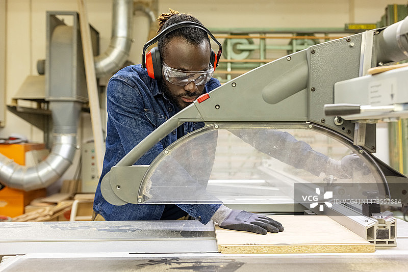 木匠在木工车间用圆锯切割木板图片素材