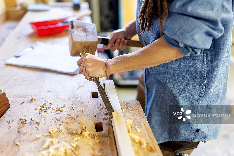 女木匠在工作室用凿子和木槌雕刻木头的特写图片素材
