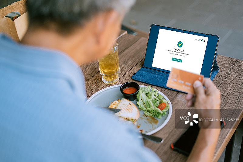 数字包容性：年长的亚裔公民在咖啡馆采用技术进行无缝在线交易图片素材