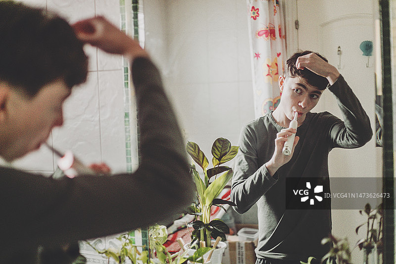 青少年男孩在浴室用电动牙刷刷牙图片素材