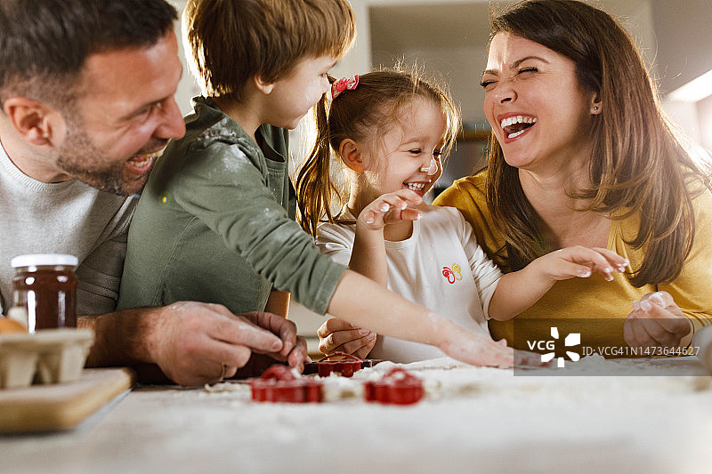 快乐的父母和他们的孩子在厨房里做饼干图片素材