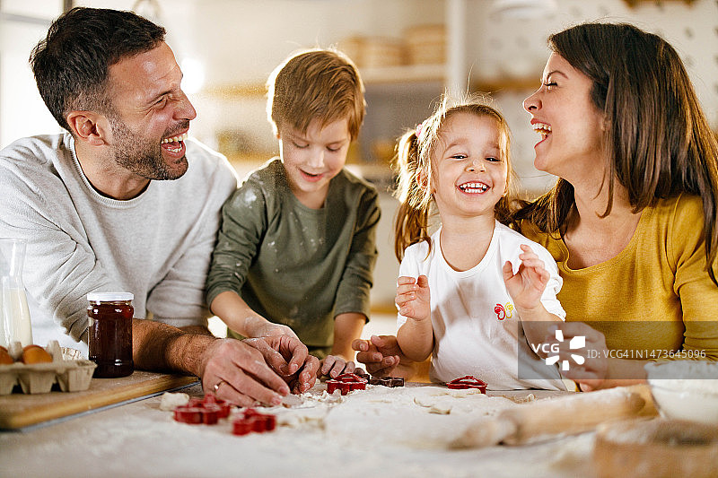 快乐的家庭在厨房合作制作蛋糕图片素材